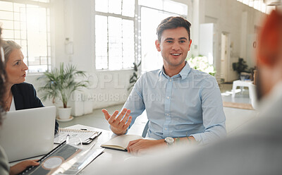 Buy stock photo Group of businesspeople talking in a meeting together at work. Business professionals talking and planning in an office. Young caucasian  businessman sitting and talking to colleagues at a table