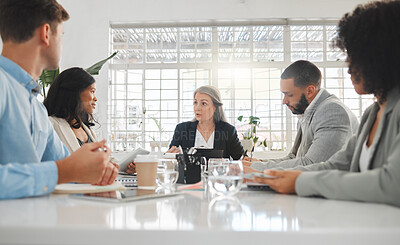 Buy stock photo Mature caucasian businesswoman explaining an idea in a meeting at work. Group of businesspeople having a meeting together at a table. Business professionals talking and planning in an office