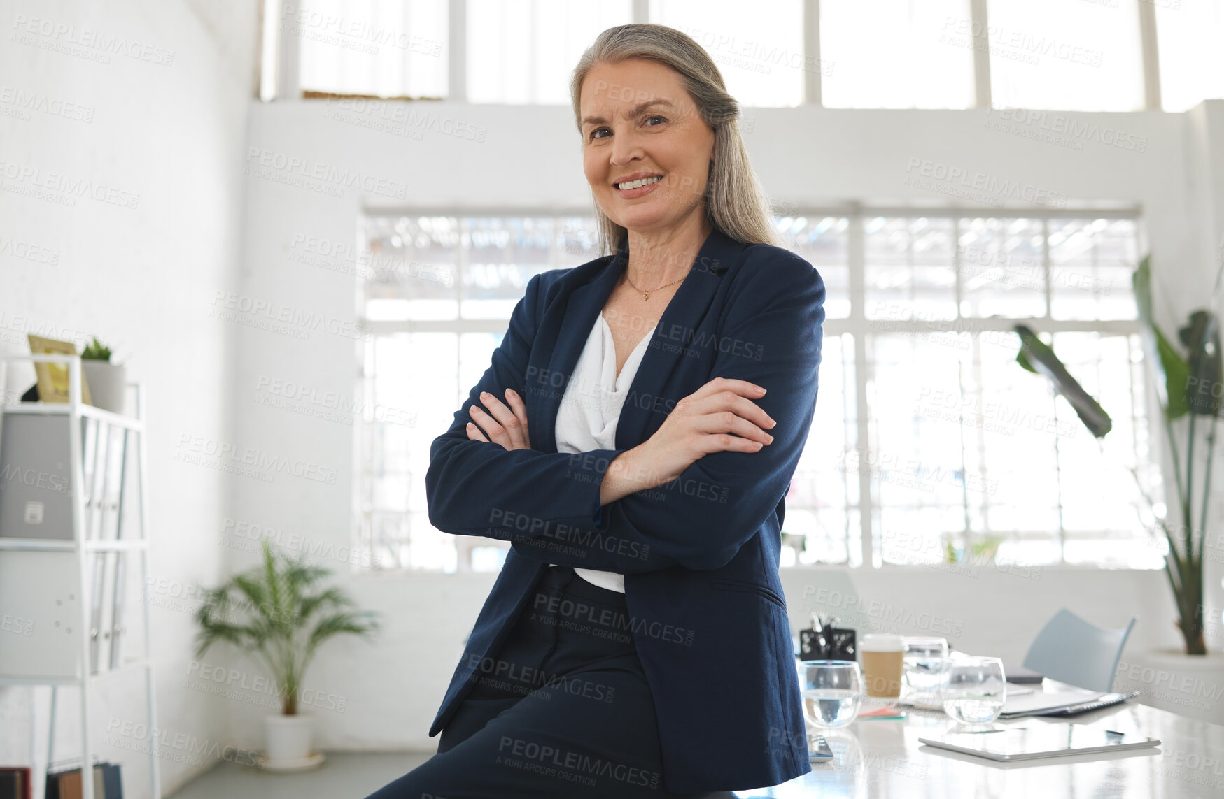 Buy stock photo Mature happy caucasian businesswoman standing with her arms crossed while in an office alone. One confident female manager smiling and standing at work