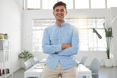 Buy stock photo Young happy caucasian businessman standing with his arms crossed while in an office alone. One confident male boss standing at work
