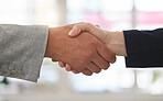Two businesspeople shaking hands while in an office together at work. Business professionals greeting networking and making deals with each other. Boss hiring an employee