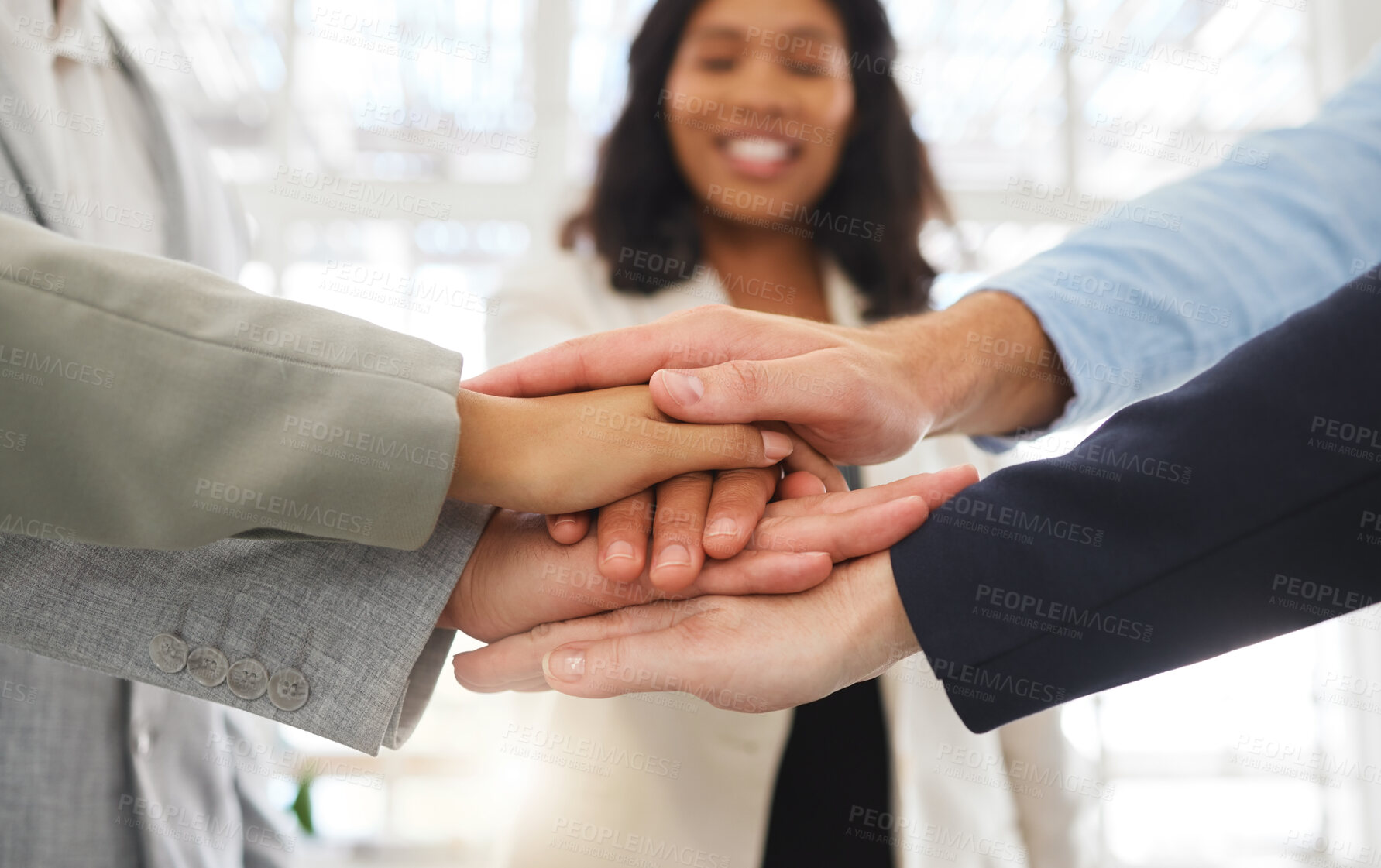Buy stock photo Group of businesspeople stacking their hands together in an office at work. Business professionals having fun standing with their hands piled for motivation during a meeting