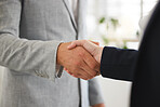 Two businesspeople shaking hands while in an office together at work. Executive business professionals greeting networking and making deals with each other. Boss hiring an employee