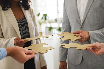 Buy stock photo Group of businesspeople holding and fitting puzzle pieces together in an office at work. Business professionals solving a jigsaw problem in a meeting