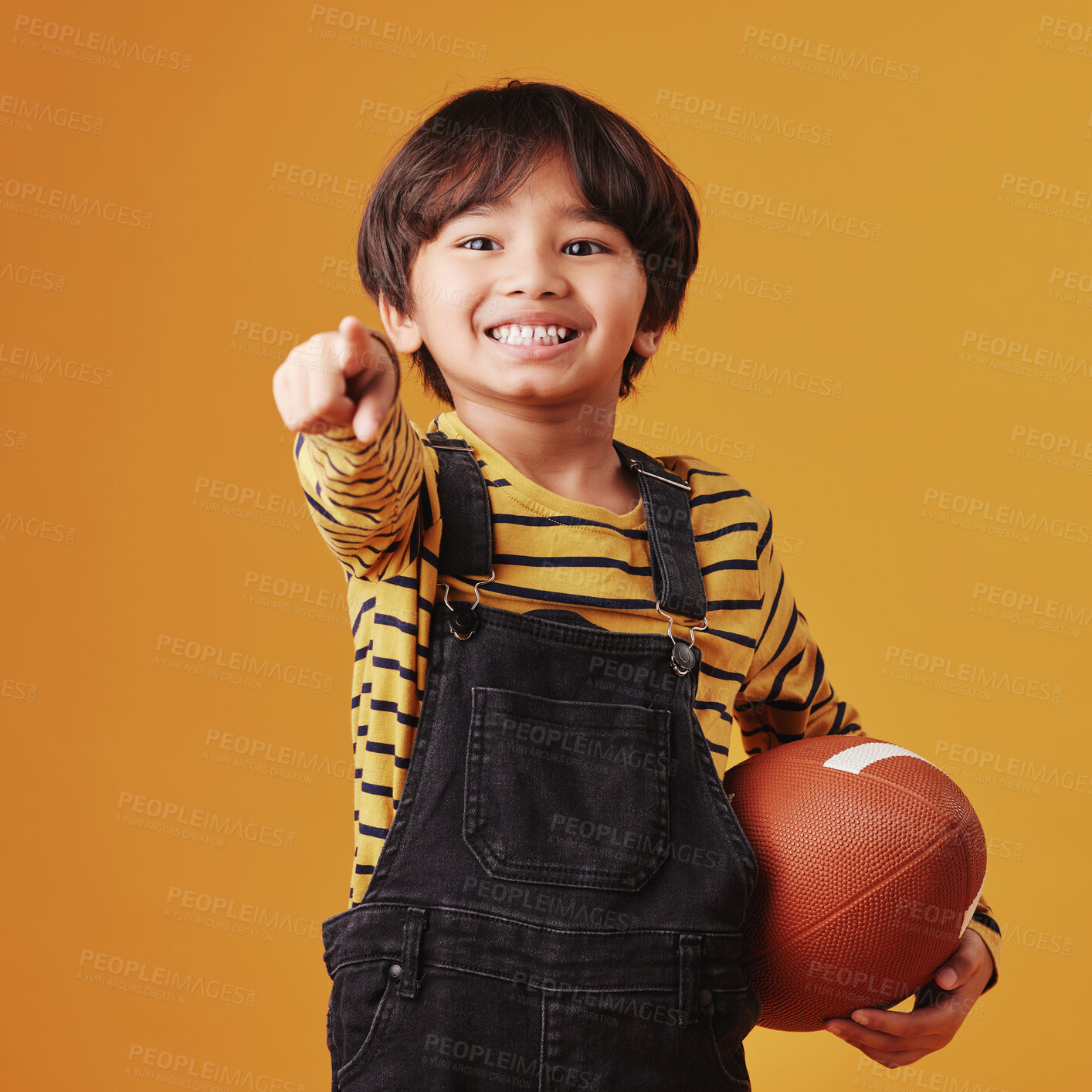 Buy stock photo Portrait, pointing to you and boy with football, child and fitness on yellow studio background. Face, kid and player with hand gesture, promotion for sports announcement and opportunity for athlete