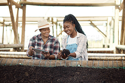 Buy stock photo Two farmers checking soil quality. African american farmer holding dirt. Two colleagues checking soil quality on a farm. Happy farmers using a digital tablet. Two women working on a farm