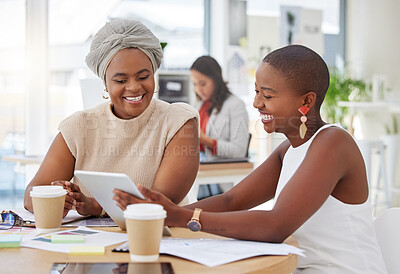 Smiling african american business women sitting together and using a digital tablet during a brainstorm meeting in the office. Confident happy black professionals planning a strategy with technology