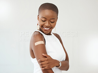 Buy stock photo Black woman, covid plaster and arm or smile in studio for injection with medical insurance. African female happy on a white background with healthcare vaccine, safety compliance and mockup space