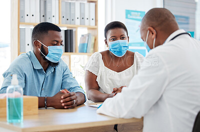 Young couple wearing covid masks during medical consult.Specialist talking to married couple about ivf treatment. African american couple in checkup for fertility. Expert doctor talking to patients