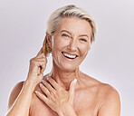 One mature caucasian woman brushing  her hair to remove knots and tangles against a purple studio background. Happy older woman styling her hair