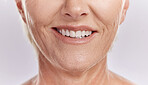 Happy mature caucasian woman with a bright smile, showing her natural looking veneers while posing against a purple copyspace background. Older woman happy with her oral hygiene while doing skincare