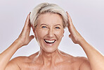 Portrait of a smiling  mature caucasian woman touching her short grey hair against a studio background. Happy senior woman smiling with glowing radiant skin against purple copyspace