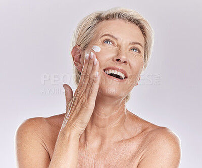 Buy stock photo Woman with sunscreen on face for beauty skincare, showing cosmetics with smile and care for skin wellness standing on grey studio background. Content elderly model doing self care with cream