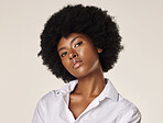 Studio portrait of a young stunning African American woman with a beautiful afro. Confident black female model showing her smooth complexion and natural beauty while posing against a grey background