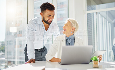 Two happy diverse colleagues working together on a laptop and digital tablet device in an office boardroom. Young mixed race businessman meeting with mature caucasian businesswoman to discuss strategy plans and ideas