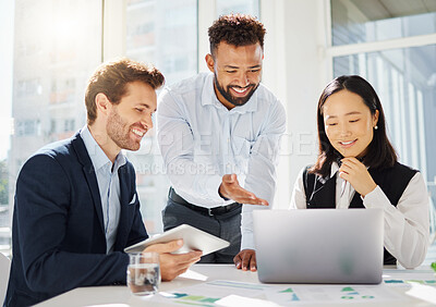 Group of happy young diverse colleagues working together on corporate plans in an office boardroom. Mixed race businessman pointing to laptop while explaining ideas to his caucasian and asian coworkers