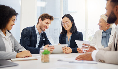 Happy young diverse colleagues discussing plans and ideas together on a digital tablet device during a meeting in an office boardroom. Asian businesswoman and caucasian businessman brainstorming online while presenting feedback to their team
