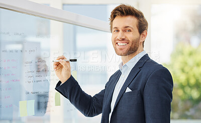 One confident young caucasian businessman writing ideas on a glass wall while planning a project in an office. Ambitious entrepreneur brainstorming a solution and marketing strategy