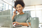 Happy mixed race woman on a call with her phone while working on a laptop sitting at a table at home. Cheerful hispanic female with a curly afro laughing while talking on the phone and typing an email alone in the lounge at home