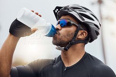 Buy stock photo Close up of male cyclist taking a break and drinking water from a bottle. Fit young man wearing glasses and a helmet while drinking water and standing outside. Athletic man cycling in nature environment 