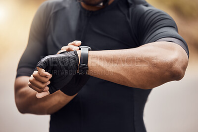 Closeup of unknown indian man standing alone outside and using his smartwatch to time his workout and check his pulse after exercising. Fit and active athlete monitoring his heart rate after training