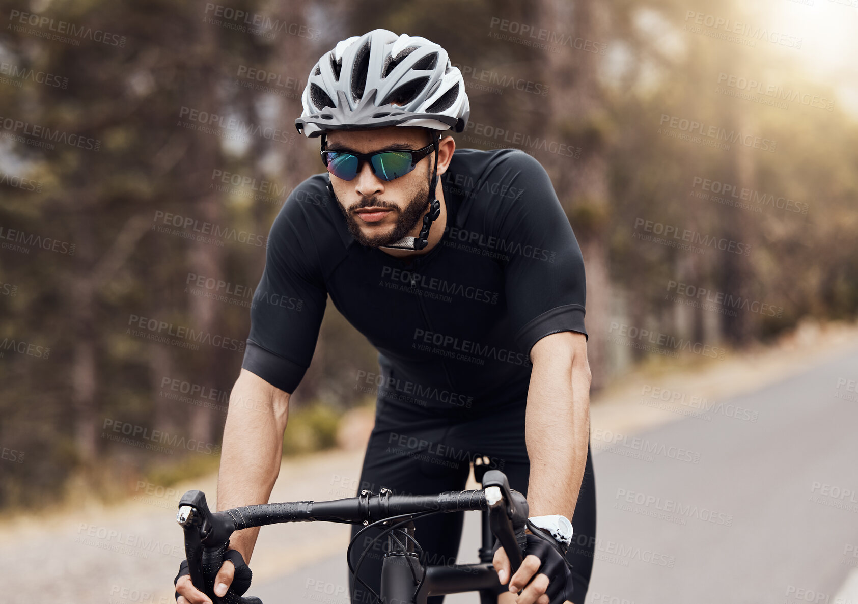 Buy stock photo One athletic young man cycling outside. Sporty fit male wearing helmet and glasses while riding a bike on a road along the mountain for exercise. Endurance and cardio during a workout and training