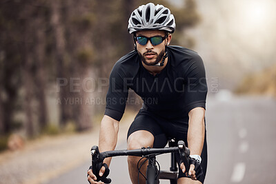 One athletic young man cycling outside. Sporty fit male wearing helmet and glasses while riding a bike on a road along the mountain for exercise. Endurance and cardio during a workout and training