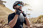 Athletic cyclist wearing glasses and gloves while tying his cycling helmet. Fit man putting on a helmet for safety. Professional cyclist getting ready to ride his bike in nature environment 