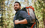 One happy mature caucasian man carrying a backpack and hiking alone in the woods during the day. Fit and active male enjoying a trek, exercise and adventure while exploring the beauty of nature alone
