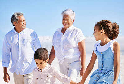 Buy stock photo Adorable little boy and girl holding hands while walking along the beach with their grandparents during summer vacation. Mixed race sibling brother and sister spending family time with grandma and grandpa by the sea