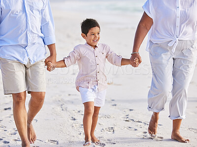Buy stock photo Adorable little boy smiling while walking on the beach with his grandparents and holding hands. Cute mixed race boy enjoying family time at the beach
