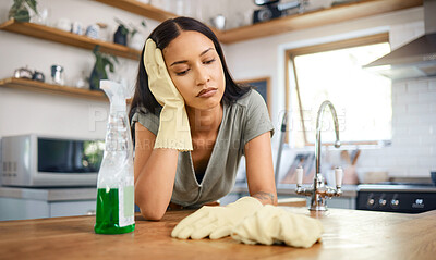 Buy stock photo Young mixed race woman looking tired while taking a break from cleaning in the kitchen at. home. Young hispanic woman looking bored while cleaning her kitchen table at home