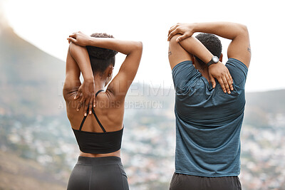 Rearview fit african american couple stretching with their arms raised before exercising outdoors. Young athletic man and woman warming up for a workout outside. They love to exercise together