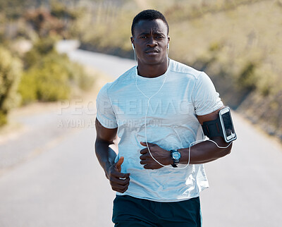 One handsome young african american athlete listening to music while out for a jog in nature. Dedicated black man working out alone outside. His fitness routine includes running to increase endurance
