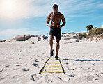 One sporty athletic african american man using an agility ladder during his training in the sand at the beach a sunny day. Fit male sportsman exercising shirtless during the day. Dedicated to health