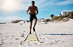 A handsome young african american male athlete working out on the beach. Dedicated black man exercising with sports equipment outside on the sand. Committed to a healthy lifestyle and getting fit