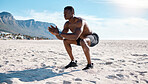 Fit young black man doing squat exercises on sand at the beach in the morning. One muscular male bodybuilder athlete with six pack abs doing bodyweight workout to build strong core, tone and endurance