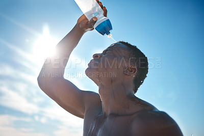 Buy stock photo Closeup shot of a young african american splashing his face with water while exercising at the beach. Black male using water bottle to cool down during a summer workout outside. focused on cardio