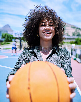 Happy young hispanic woman about to workout holding a basketball while standing on a court. Portrait of smiling girl about to play basketball holding and showing the ball outside.