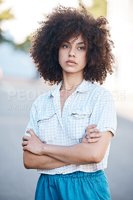 Buy stock photo A young female mixed race woman standing with her arms crossed outside looking cool and confident with great style. Hispanic hipster woman with a curly afro in a cool outfit against a urban background