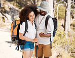 A young couple using a smartphone outdoors while on a hike in nature. Mixed race woman and african american male smiling and enjoying a n Hike in a forest while using a gps on a mobile device