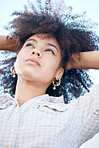 Closeup shot of a beautiful young mixed race female with her hands in her afro. Below shot of one african american woman looking thoughtful and contemplative while standing outside. Full of ideas