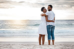 Portrait of a young happy african American couple spending a day at the sea together. Cheerful boyfriend and girlfriend watching the view on the beach. Loving husband and wife smiling while standing on the beach