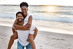 Young happy african American couple spending a day at the sea together. Cheerful boyfriend giving his girlfriend a piggyback on the beach. Loving husband and wife bonding on the seashore