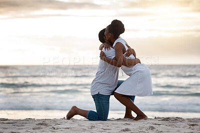 Buy stock photo Boyfriend asking his girlfriend to marry him while standing on the beach together. African american man proposing to his girlfriend by the seashore. Young happy couple hugging after getting engaged on holiday