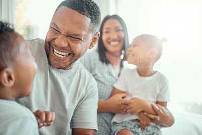 Buy stock photo Happy funny mixed race family with two children wearing pyjamas and sitting together at home. Cheerful father laughing and playing with his son while having fun at home