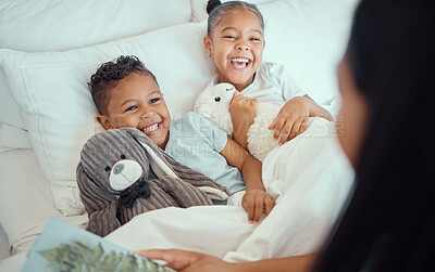 Happy little sibling brother and sister lying comfortable in bed while mother tucks them in while reading story book before bedtime or to wake them up in the morning. Cheerful little girl and boy sharing a bed