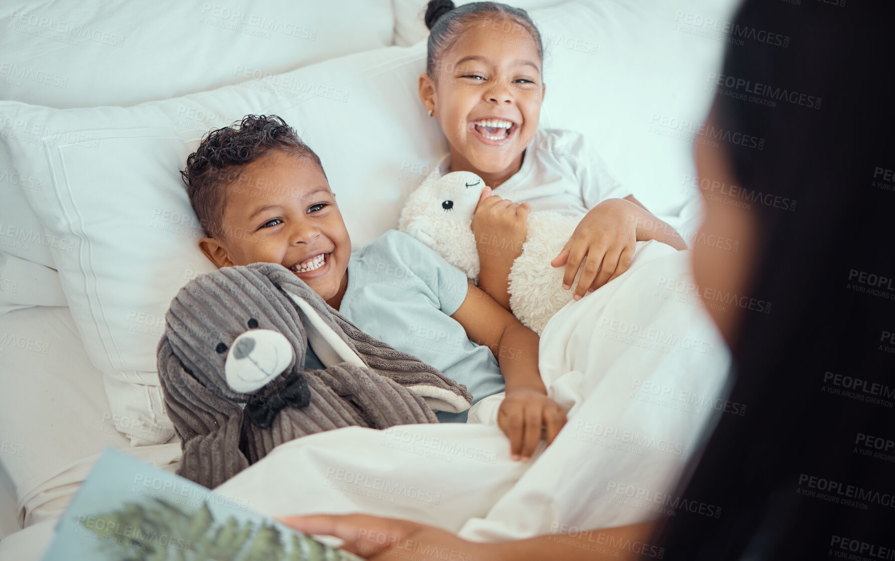 Buy stock photo Happy little sibling brother and sister lying comfortable in bed while mother tucks them in while reading story book before bedtime or to wake them up in the morning. Cheerful little girl and boy sharing a bed