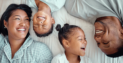 Buy stock photo Happy laughing mixed race family with two children relaxing and lying together on a bed at home, from above. Faces of little brother and sister spending time with their loving parents