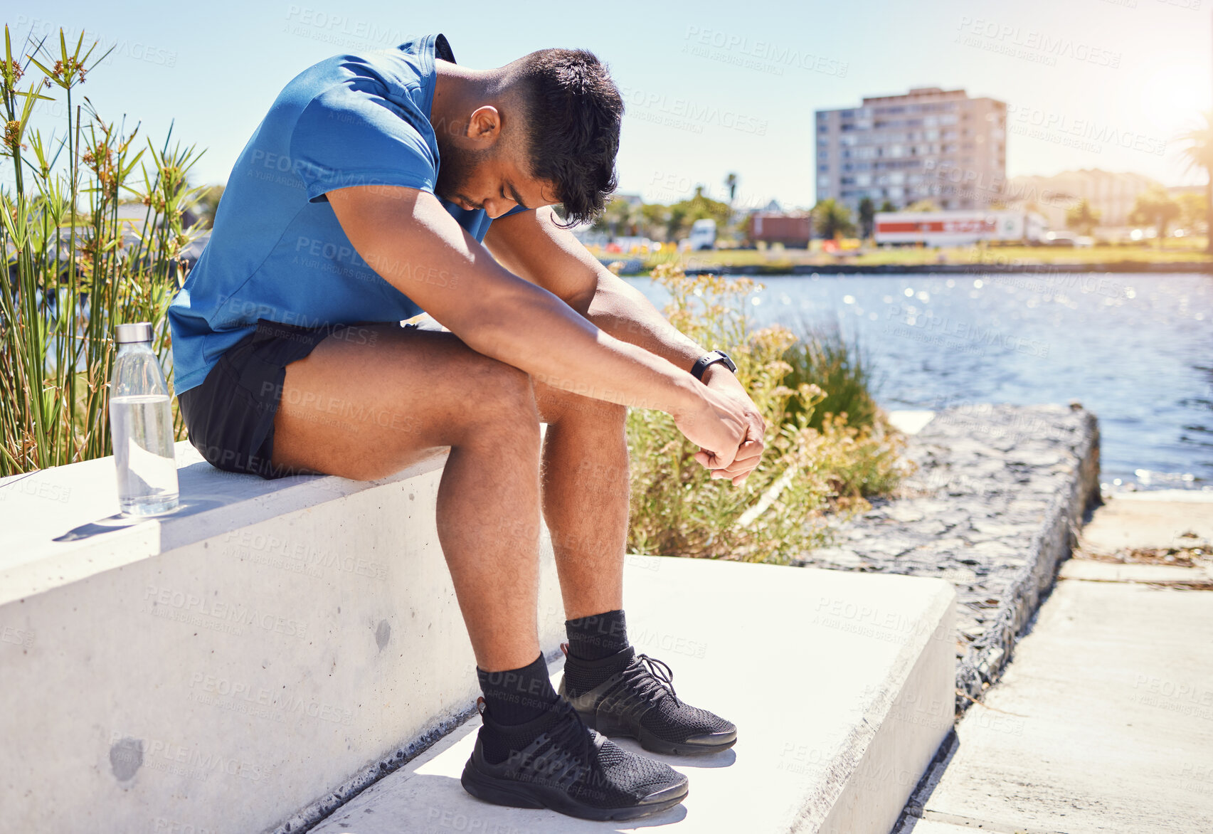 Buy stock photo One young mixed race man sitting and taking a break from exercising outside. Exercise helps with depression and anxiety. Hispanic man looking exhausted and low on energy while training outdoors